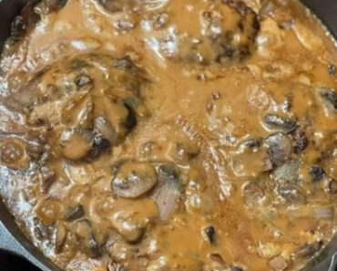 Hamburger steak smothered in brown gravy with mushrooms and onions